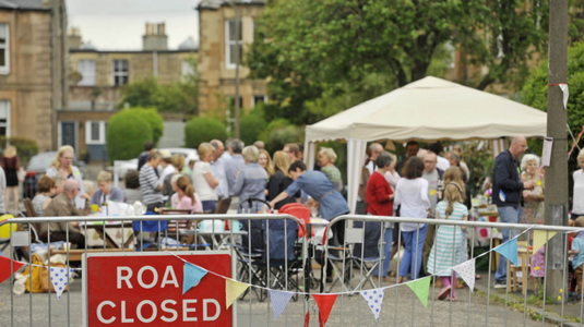 Street party in full swing with a barrier and road closed sign