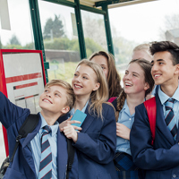 Young people in school uniform standing at a bus stop
