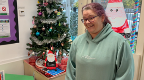 A woman wearing a mint coloured hoodie, smiling while stood in a family hub with Christmas decorations in the background.
