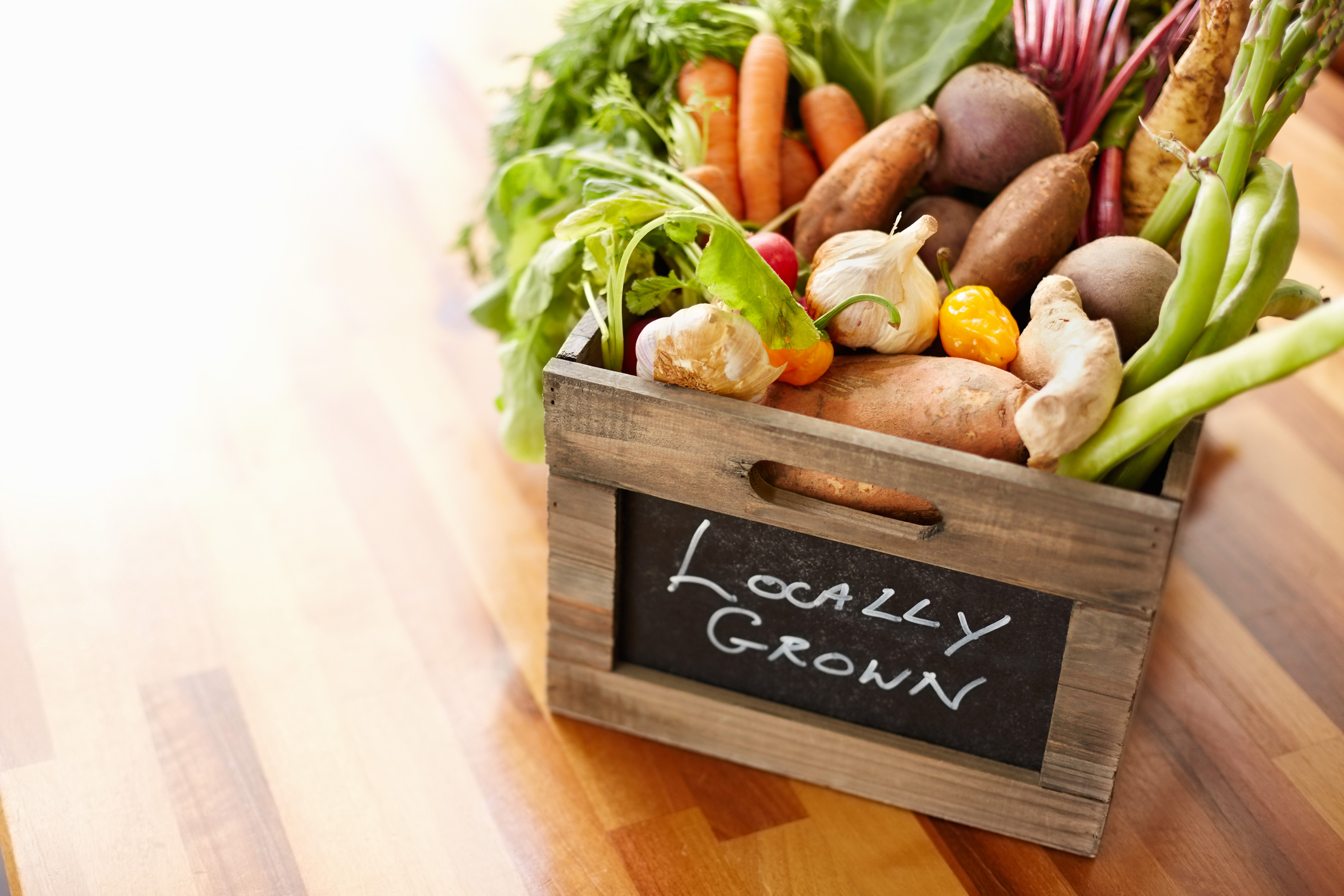 A box of fresh vegetables with the words locally grown written on the front of the box
