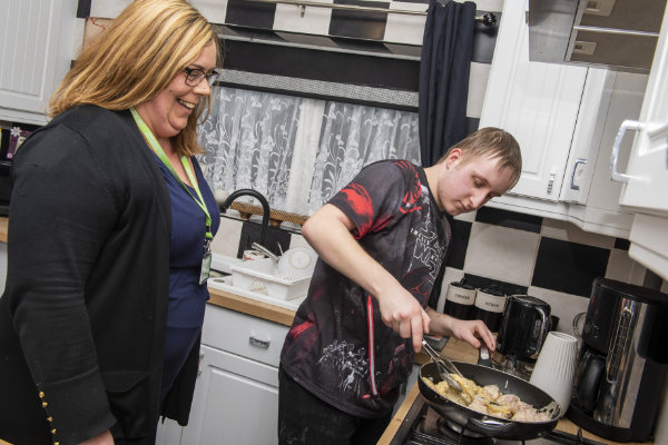 Woman watching a young man cook food on a stove