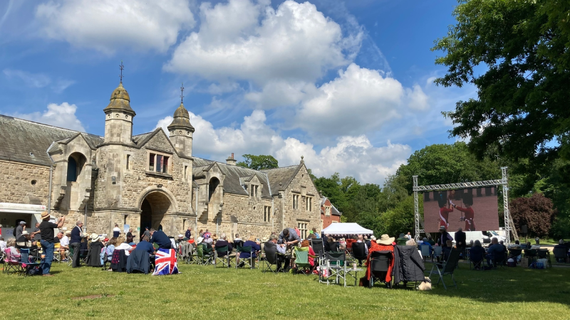 Thoresby Veteran's event on the lawn with a large screen and lots of people seated, watching the screen