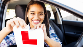 Young person smiling and ripping up learner driver L Plate