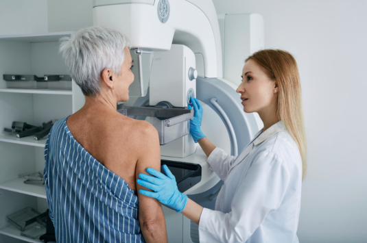 Woman stood at a breast screening machine being operated by a healthcare worker