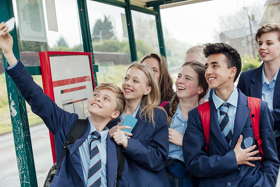 Young people in school uniform standing at a bus stop