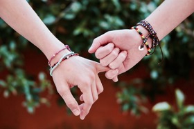 A couple linking hands by their little fingers