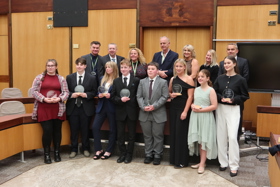 4Uth award district winners and standing with the awards. Behind them are the people that nominated them for the award.