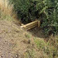 Leaky barrier made up of wooden logs in Ompton
