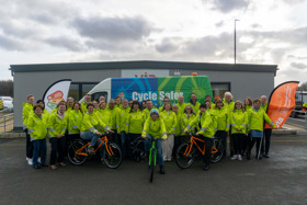 Group from Via's Bikeability team all wearing yellow high-Vis jackets with new bicycles - 2 orange and 1 green